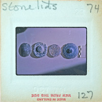 Photo of four small stone lids with various decorations on a surface.