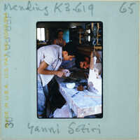 Two people at workbench restoring terracotta statue while another looks on.