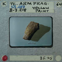 A small yellow rock on a white surface with a label and barcode.