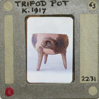 A reassembled clay pot with a handle and three legs on a table