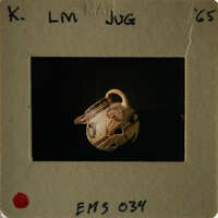 A small, intricately decorated vase with a handle on display.