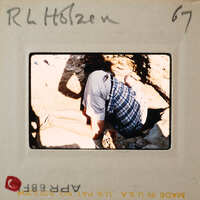 Person kneeling down, looking at something on the ground.