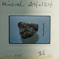 A photograph of a rock specimen on a label with handwritten notes.