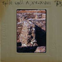 A photograph of a stone wall with visible damage, possibly from an explosion or natural disaster.