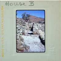 Old stone ruins with a blue sky and mountains in the background, photographed on an old film strip.