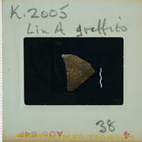 A small, irregularly shaped rock on a film negative with handwritten notes and numbers.