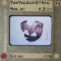 Ancient ceramic artifact with intricate designs and visible cracks, photographed on a white background.