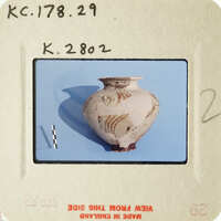 Old photograph of an ancient vase with markings, displayed on a light blue background.