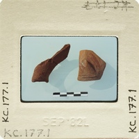 Two ancient clay objects on display, possibly artifacts with labels and measurements.