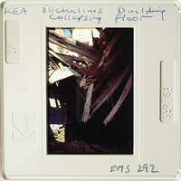 A photograph depicting an interior with wooden beams and debris, possibly from a collapsed structure.