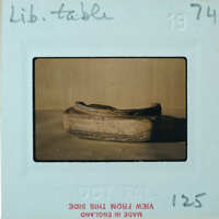 Fragment of squared off stone with rim and circular impression on top.