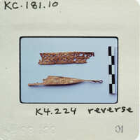 Two small, gold-colored artifacts with intricate designs on a white background.