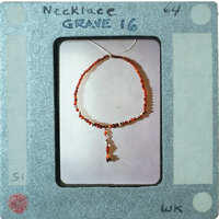 A bracelet with red and black beads on a display card.