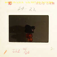 Small figurine with red and black colors on a white surface.