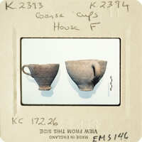 Two clay cups on display, with one having a handle and the other without.