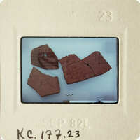 Broken brown pottery on a white surface.