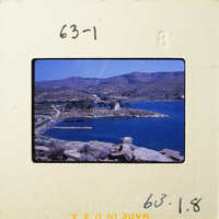 A photograph of a scenic coastal landscape with mountains, water, and greenery.