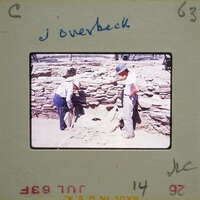 Two men working on a stone structure, possibly an archaeological site.