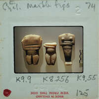 Three small figurines displayed on a white surface with labels.