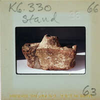 A photograph of a broken, brownish artifact with ancient markings on it.