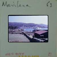 A vintage photograph of a coastal landscape with hills, water, and buildings.