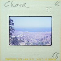 A photograph of a coastal landscape with hills and blue water, enclosed within an old film strip.