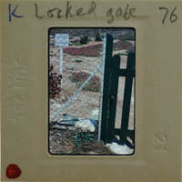 A photograph of a locked gate with a fence and flowers, displayed on a film strip.