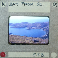 A vintage film strip showing a scenic view of a bay with mountains and boats.