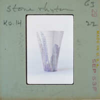 A photograph of a ceramic vase with an intricate design, displayed on a vintage postcard.