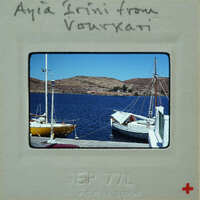 A vintage photo of a harbor with boats and hills in the background.