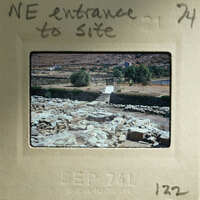 An old photograph of a stone ruins with handwritten notes on the border, indicating it's an entrance to a site and possibly related to a historical event or location.