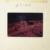 This is an image of a photographic negative with a scene featuring a rocky landscape and a body of water, as well as some structures or ruins.