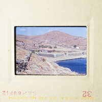 A scenic landscape featuring a village and mountains, captured on an old photograph.