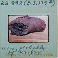 A close-up photograph of a rock with an old Polaroid border and handwritten notes on the back.