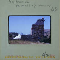 The image is a photograph of an old stone tower with a blue sky and hills in the background, taken by someone named Marina.