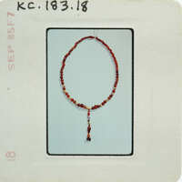 A photo of a red rosary bead necklace with a cross pendant.
