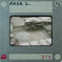 The image shows a photograph of an archaeological site with stone ruins, placed within a mockup of a Polaroid-style photo frame.