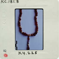 Necklace of red beads on white background.