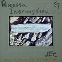 Old photo of a rock with writing on it, displayed on an aged piece of paper.