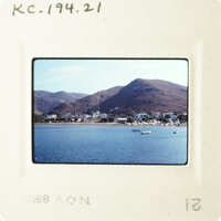 A tranquil coastal scene with boats on the water and mountains in the background.