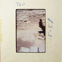 This is an old photograph showing ruins with stone walls and foundations, possibly from an ancient civilization.