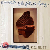 The image is of a small, ancient clay figurine with intricate designs and patterns on it.