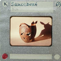 A photograph of a clay pot with an animal shadow on it, placed within a film strip frame labeled "Sauceboat" and numbered 69.