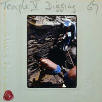 Two men excavating a muddy surface.