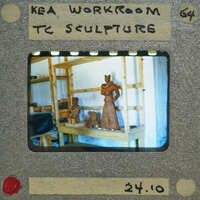 A photograph of a sculpture workshop with clay figures on shelves and workbenches.