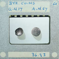 Two small coins displayed on a white surface with labels and numbers written around them.