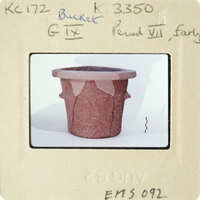 Old clay pot on white surface with handwritten labels and numbers.
