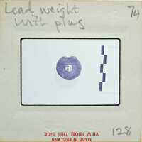 A small, purple gemstone with a white background and measurement lines on a card.