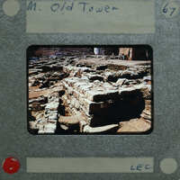 A photograph of an old stone tower with visible ruins and a red dot on the bottom right corner, possibly indicating its location or status.