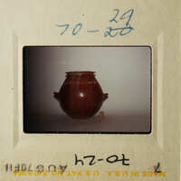 The photo shows an antique vase on display, with a small white tag attached to it.